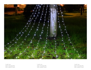 Outdoor LED star waterfall lights cascading from trees onto grass in white cold glow