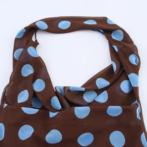 Close-up of brown chiffon fabric with blue polka dots featuring a halter neckline detail