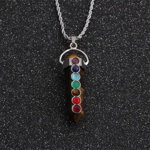 Macro detail of silver twist chain with seven-chakra stone pendant on a dark background