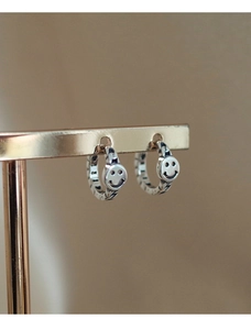 Macro shot of vintage silver smiley face earrings with twisted texture on a gold stand