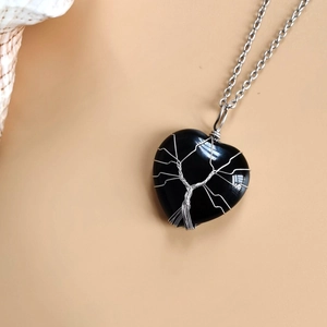 Macro shot of heart-shaped black stone pendant with silver wire-wrapped tree of life