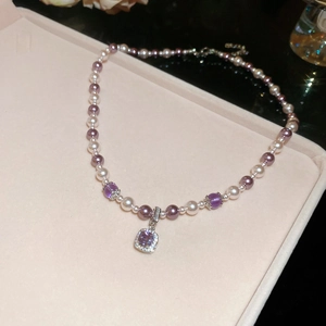 Detail of zircon manta rose pearl necklace with purple square crystal pendant on velvet
