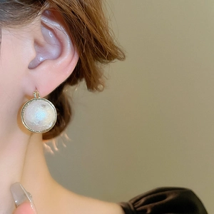 Gros plan de boucles d'oreilles perles baroques françaises avec finition dorée sur modèle