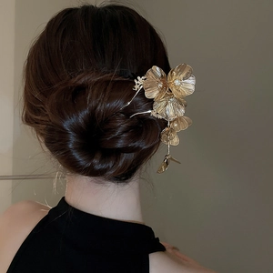Detailed view of champagne gold floral hair pin with diamond accents on dark hair