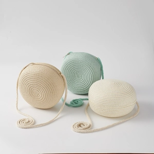 Detailed view of round woven straw bags in beige, light green, and white colors