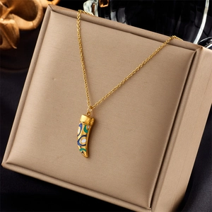 Golden horn pendant necklace with blue enamel swirls on beige jewelry box cushion