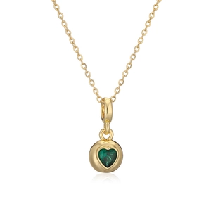 Close-up of golden necklace with circular pendant featuring a green heart-shaped gemstone