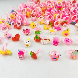 Gros plan de bagues roses pour enfants en plastique avec breloques d'ours et de fruits