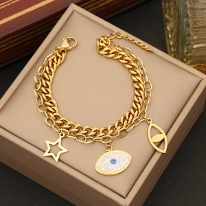 Double-layered gold chain bracelet with evil eye and hollow star charms on beige box