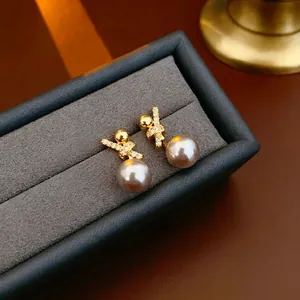 18k gold plated pearl earrings with zircon cross design in a gray velvet jewelry box