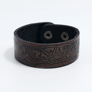Close-up of embossed Celtic patterns and knotwork on a dark brown leather bracelet