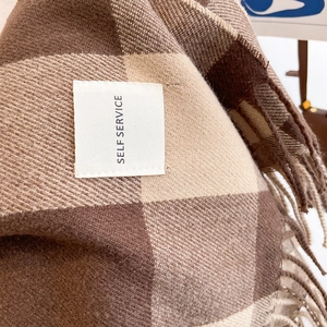 Macro shot of brown plaid cashmere-like scarf texture with fringe and woven label