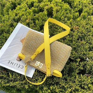 Detailed top view of a woven straw beach bag with a golden metal twist lock and yellow strap