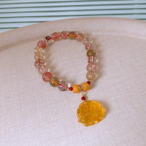 Close-up of beaded rutilated quartz bracelet with a yellow lotus flower charm