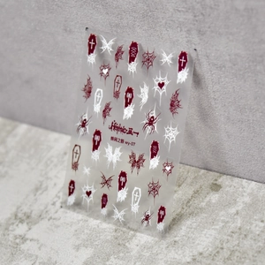 Close-up of gothic nail stickers with spider web and cross motifs in dark red and black