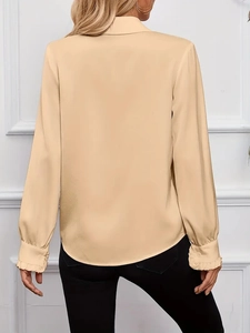 Dettaglio dei polsini a balze e del tessuto beige su una camicia a maniche lunghe da donna