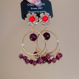 Detailed view of bohemian style round drop earrings with red beads and rhinestones
