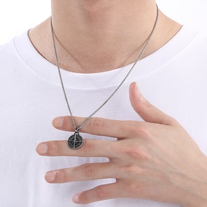 Close-up of men's stainless steel compass pendant necklace on a white t-shirt