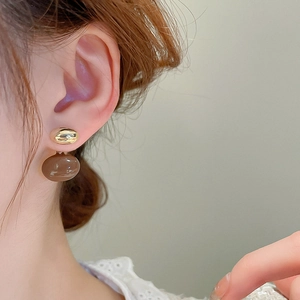 Gros plan de boucles d'oreilles ovales dorées avec pendentif en résine marron sur modèle