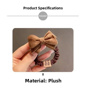 Close-up of brown plush bow hair tie with Hand Made label and soft textured material