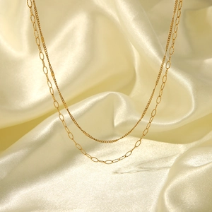 Detailed close-up of double-layered gold stainless steel necklace on elegant silk