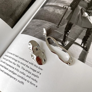 Detailed view of asymmetric 925 sterling silver earrings displayed on a fashion magazine