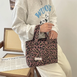 Detail of leopard print faux fur handbag featuring a woven white label on soft texture