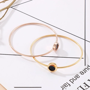 Detail of rose gold and gold bracelets featuring round black enamel and LOVE engraving