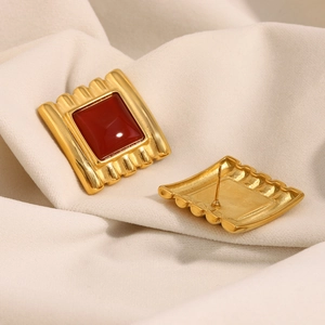 Macro view of vintage 18K gold plated square stud earrings with red gemstones and serrated edges