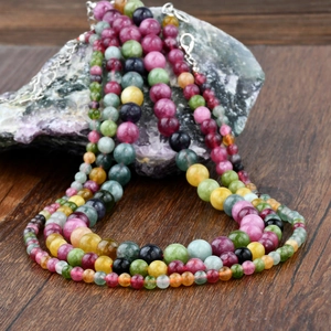 Detail view of colorful vintage tourmaline beaded necklace on stone and wood background