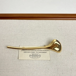 Close-up of minimalist gold streamlined brooch on a rustic textured linen background