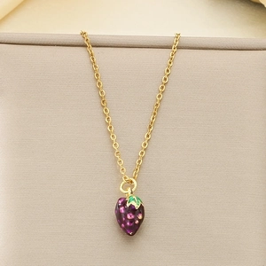 Detail shot of a purple grape pendant with green enamel leaf on a gold-plated chain necklace