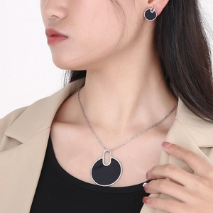 Close-up of minimalist black geometric pendant necklace and earrings set on model