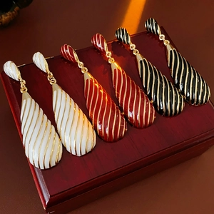 Gros plan de boucles d'oreilles vintage en blanc, rouge et noir avec rayures dorées