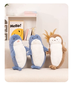 Close-up of cute plush shark, narwhal and sea otter bolsters on a cream sofa