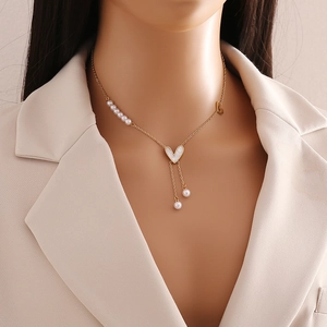 Detail of gold heart pendant necklace with pearl fringe and layered chains on model