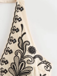 Detail of floral black embroidery and mirror sequins on beige halter neck top