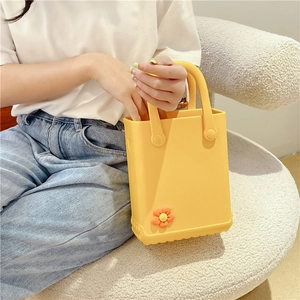 Yellow EVA beach tote bag with orange flower charms held by a model on a sofa