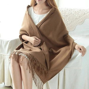 Brown plaid cashmere-feel scarf with tassels worn by a model in a cozy home setting