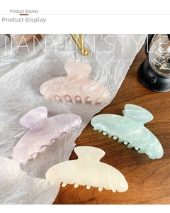Detail of four colorful iridescent acrylic hair claws with marble texture on a desk