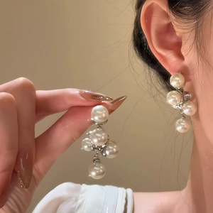 Detailed view of elegant silver post pearl grape drop earrings worn on the earlobe
