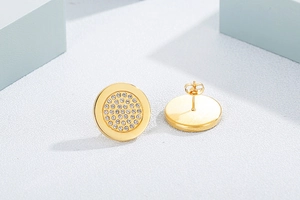Detailed macro view of gold-plated round earrings featuring pave-set white crystals