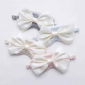 Stack of satin silk sleep masks with large bows in grey, blue, beige and pink