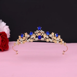 Detail of baroque gold crown with blue crystal gems and white diamonds on black background