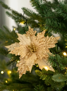 Golden sequin poinsettia flower ornament detailed on a green Christmas tree branch