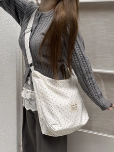 Detail of white canvas crossbody bag with blue star patterns and branded fabric label