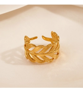Macro shot of gold-plated hollow leaf ring with intricate texture on beige fabric