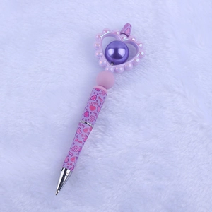 Detail of purple cartoon heart bead pen with LOVE pattern on white plush background