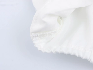 Detailed close-up of white polyester fabric texture with elastic band and neat stitching