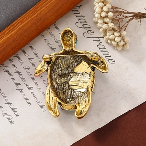Vintage gold sea turtle brooch featuring a classic safety pin on retro letter paper